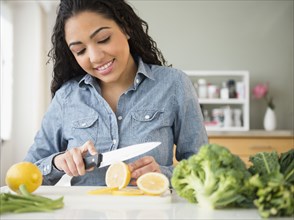 Hispanic woman slicing lemon in kitchen