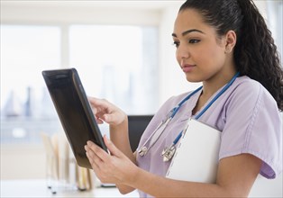 Hispanic nurse using tablet computer in hospital