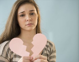 Hispanic girl holding broken heart shape