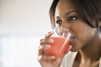 African American woman drinking glass of juice