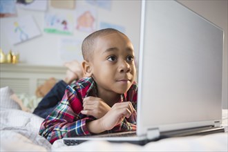 African American boy using laptop on bed