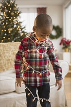 African American boy wrapped in Christmas lights