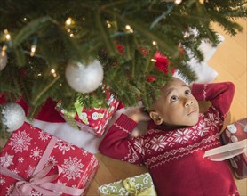 African American boy laying under Christmas tree