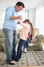 Father playing with daughter in living room