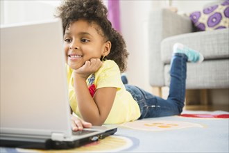 African American girl using laptop on floor