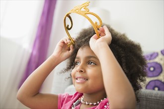 African American girl putting on toy crown