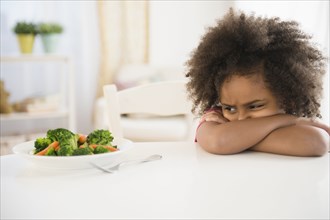 African American girl refusing vegetables at table
