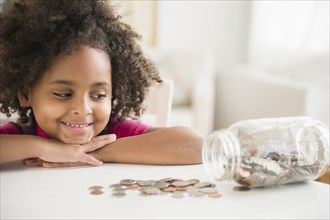 African American girl counting change in jar