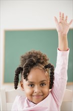 African American girl raising her hand in classroom