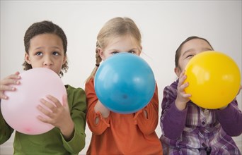 Girls blowing balloons together