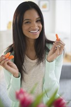 Mixed race woman holding carrot sticks