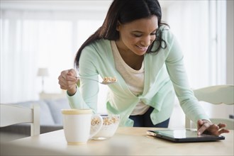 Mixed race woman using tablet computer at breakfast