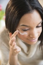 Mixed race woman applying moisturizer