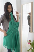 Mixed race woman admiring dress in mirror