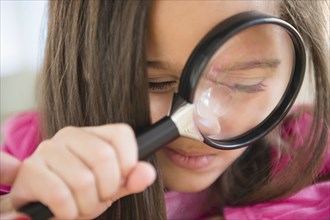 Hispanic girl using magnifying glass