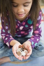 Hispanic girl holding handful of coins
