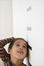 Hispanic girl measuring her height on wall