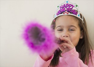 Hispanic girl using noise maker at New Years' party