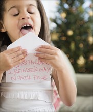Hispanic girl sealing envelope for Santa