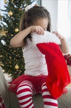 Hispanic girl examining Christmas stocking