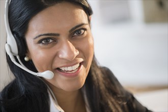 Indian businesswoman wearing headset at desk