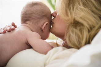 Caucasian mother kissing baby