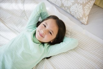 Mixed race girl smiling on bed