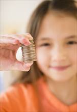 Mixed race girl holding stack of coins