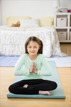 Mixed race girl meditating on yoga mat