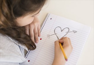 Hispanic girl doodling heart and arrow