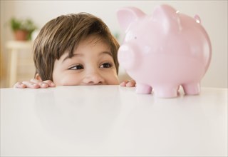 Hispanic boy examining piggy bank