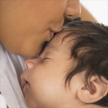 Hispanic mother kissing infant son
