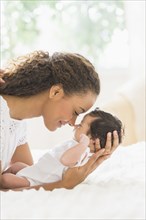 Hispanic mother holding infant on bed