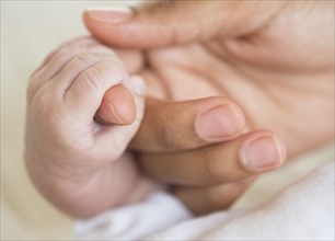 Hispanic mother holding infant's hand