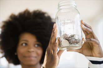 Mixed race woman holding jar of change