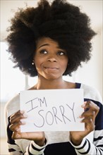 Mixed race woman holding "I'm sorry" sign