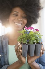 Mixed race woman holding potted flowers