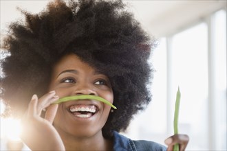 Mixed race woman playing with green beans