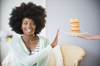 Mixed race woman refusing donuts