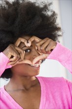 Mixed race woman making heart-shape with fingers