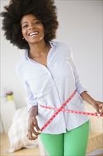 Mixed race woman measuring her waist