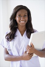 Black nurse carrying clipboard