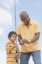 Older man teaching grandson to fish
