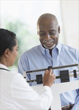 Black doctor weighing patient