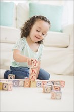 Mixed race girl playing with wooden blocks