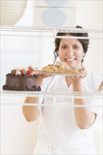 Hispanic baker holding fresh desserts