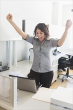 Hispanic businesswoman cheering in office
