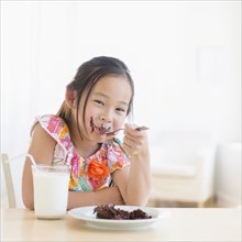 Korean girl eating slice of chocolate cake