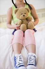 Korean girl holding teddy bear on bed