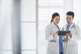 Doctors using digital tablet in hospital corridor